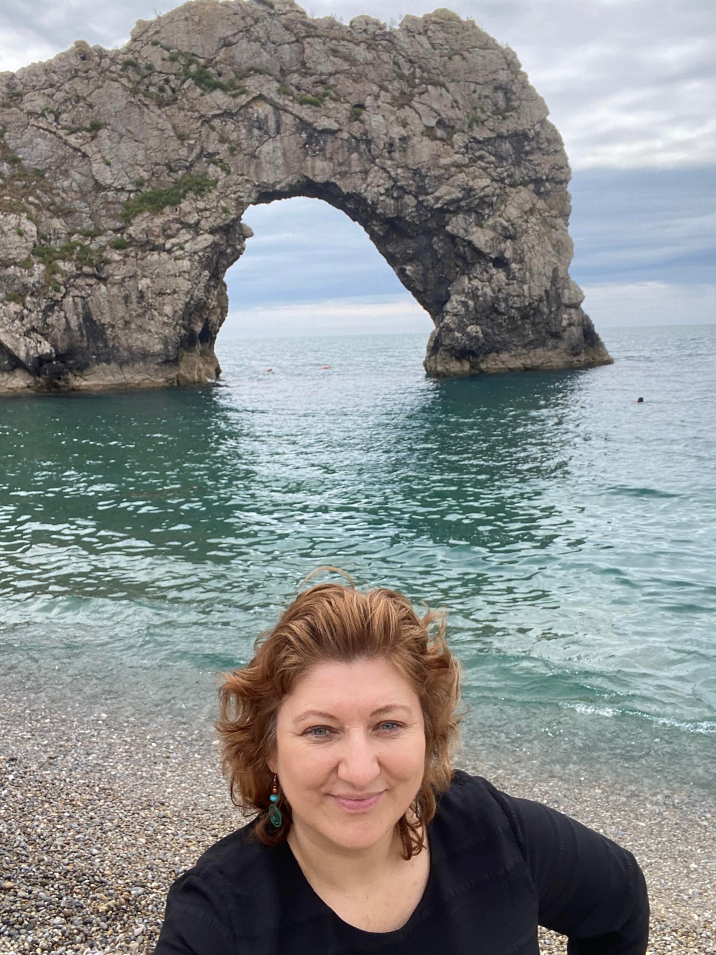 Aneta smiling on the beach in front of the Durdle Door arch in England